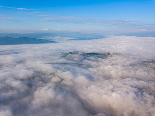 High flight above the clouds in the mountains. Aerial drone view.