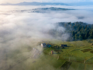 Mountain settlement in the Ukrainian Carpathians in the morning mist. Aerial drone view.