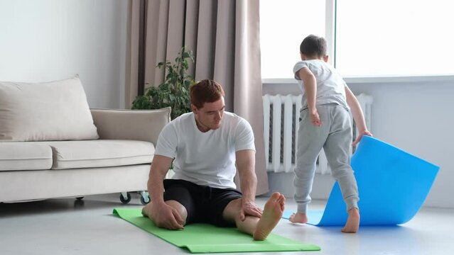 dad doing morning exercises while active energetic child son playing. father working and doing yoga exercise at home for stress relief relaxing with naughty little kid. 4k video footage slow motion.