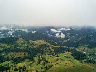 Fototapeta na wymiar Green slopes of Ukrainian Carpathian mountains in summer. Cloudy morning, low clouds. Aerial drone view.