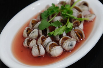close up a plate of Tegillarca granosa (blood cockle or blood clam) with cilantro. Chinese seafood cuisine