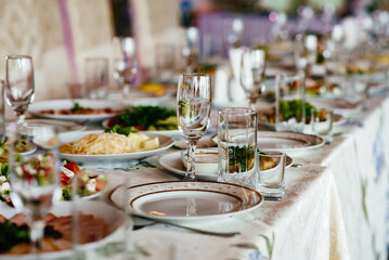Beautiful table setting with crockery and flowers for a party, wedding reception or other festive event. Glassware and cutlery for catered event dinner.