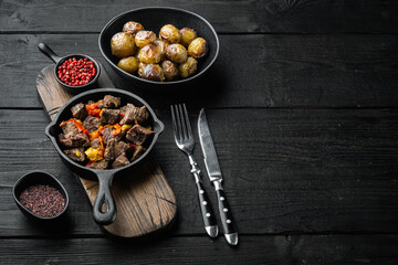Beef bourguignon stew with vegetables, in cast iron frying pan, on black wooden background, with...