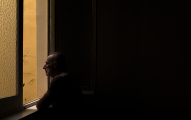 Adult man looking through window in room