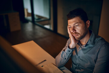 Can I please just go home already. Shot of a young businessman looking bored while working late in an office.