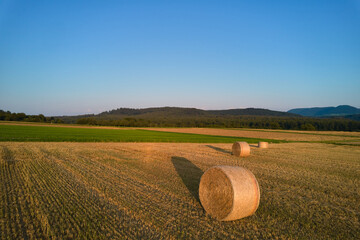 3 Straw bales on agricultural field after wheat harvest. Hills of the Swabian Alb in the background...