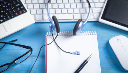 Customer service headset, computer keyboard and business objects on the blue background.
