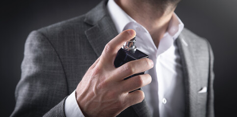 Caucasian elegant man spraying perfume.