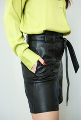 A model in light green clothes and black leather shorts. Shooting fashionable clothes for the showroom. photo studio