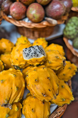 Naklejka na ściany i meble Freshly harvested yellow pitaya, pitahaya or dragon fruit, cactus fruit with fresh mangos on the market in Funchal, Madeira Islands, Portugal