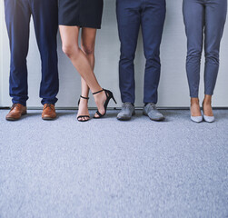 Strive for success and success will stay in your stride. Closeup shot of a group of unrecognizable businesspeople standing in line against a grey background.