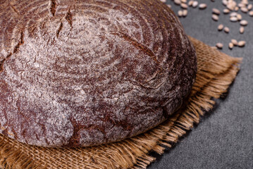 Fresh baked homemade brown bread on a black concrete background with wheat grains