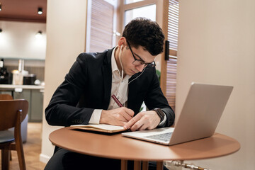 A manager with glasses, a man in informal clothes, works in an office in a coworking, uses a laptop computer
