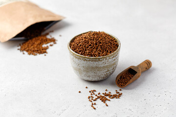 Tartary Buckwheat tea in little bowl with spoon and package on white background. Healthy ku qiao tea.