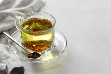 Buckwheat tea in a glass cup with grain in spoon and napkin on white background. Healthy ku qiao...