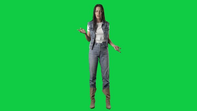 Angry young woman in jeans arguing yelling and explaining at camera. Full body isolated on green screen background
