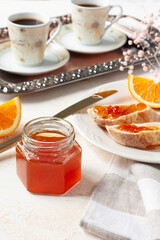 A jar of orange jam for breakfast on a light background