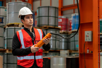 Engineering technician worker is operating the machine inside factory using hydraulic crane switch...