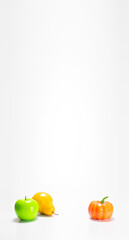 Vertical banner with fresh green apple, yellow pear and a ripe pumpkin in front of on a white background with space for text: the difference in the benefits of fruits or vegetables