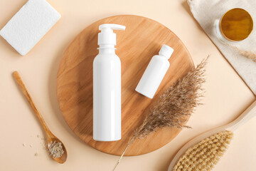 White blank cosmetic bottles, dried herbs on wooden plate. Natural skin care SPA beauty product design. Mineral organic cosmetics Mock-Up. Beige background. Face and body treatment. Flat lay, Top view