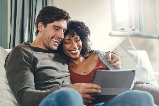 Theres always something interesting happening online. Shot of an affectionate young couple using a digital tablet together while spending some quality time together at home.