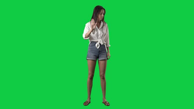 Angry woman showing various negative threat gestures at camera. Full body isolated on green screen background