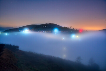 Fototapeta na wymiar Night scene hillside a small town in fog shrouded by colorful houses and lights makes night in highlands of Da Lat, Vietnam so beautiful