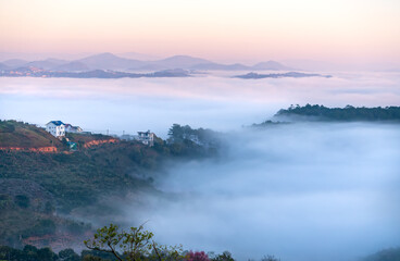 New morning scene on top hill looking down with fog covering valley and peaceful sunrise sky background in Da Lat highland, Vietnam