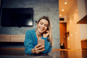 A happy woman using mobile phone on the floor at her home.