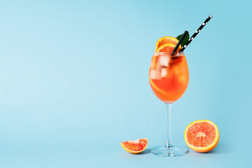Aperol spritz in glass with slice of orange on blue background