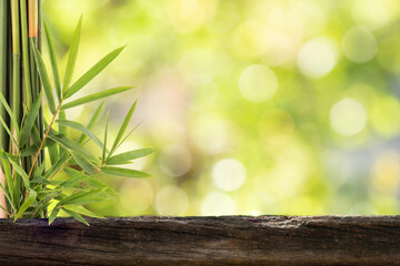 Old wood floor and bamboo green leaves on bokeh nature background.