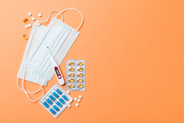 Protective face masks or surgical masks, medicine pills and thermometer on table background. Coronavirus disease. Corona virus concept. Space for text