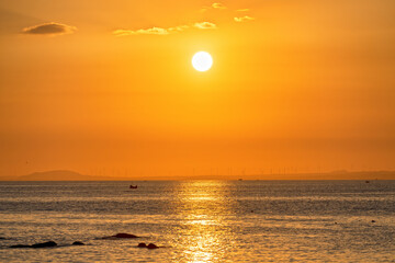 The background of the sunset on the sea as the sun gradually descends to the golden horizon in the space ending a peaceful day at sea