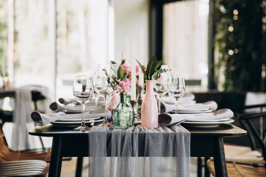Wedding. Banquet. Decor. Festive tables are decorated with fabric, compositions of flowers and greenery in glass vases, there are candles, glasses, plates and cutlery on the tables