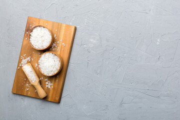 A wooden bowl of salt crystals on a wooden background. Salt in rustic bowls, top view with copy space