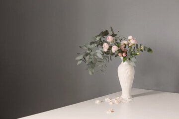 bouquet of pink roses in ceramic white vase  on background gray wall