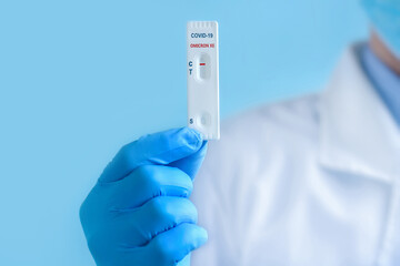 A doctor wearing a protective mask and gloves shows a rapid laboratory test for COVID-19 Omicron ??...