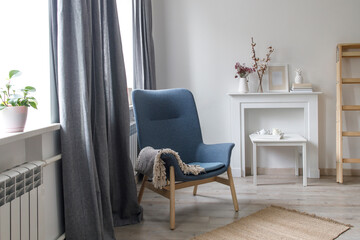 Room interior in Scandinavian style, in white and gray tones. A white wooden fake fireplace with vases of dry flowers as room decoration. Copy space
