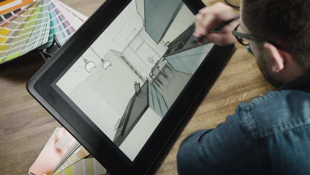 A professional illustrator designer is working on the interior of a modern kitchen. A man creates a digital image using an interactive graphics tablet
