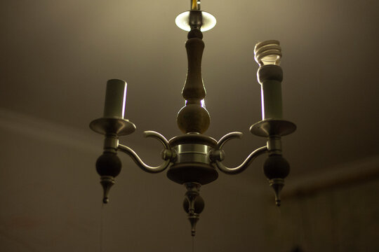 Old chandelier without lamps. Poor interior design. Lamp does not conform to cap. Chandelier made of steel and wood.