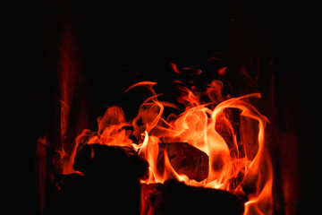 Fire flames on abstract art black background texture. Home Fire burning in brick fireplace. Seasonal and holiday fire A fire burns in a fireplace