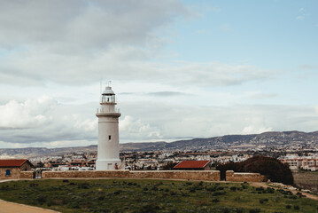 sea ​​lighthouse on the background of the city, sea shore, cute lighthouse, coastal landscape