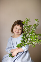 Charming european teenage girl with cherry blossom branch. Spring children's portrait. Gentle portrait of a preteen child