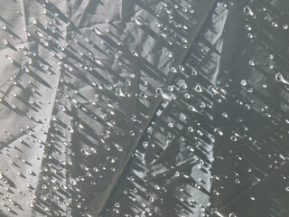 extreme close-up shot of dew drops with sunshine light all over white polyester fabric tent in the early morning