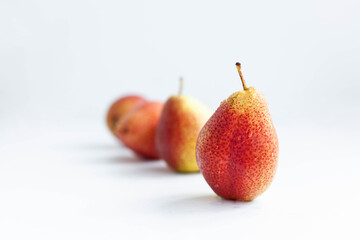 Ripe red pears lined up in a row on white background