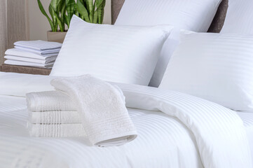 Clean white bath towels on the neatly clean bed of hotel room - coziness and clean concept