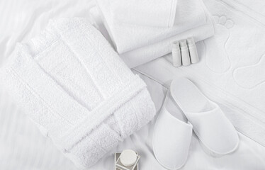Clean bathrobe with spa accessories on white background