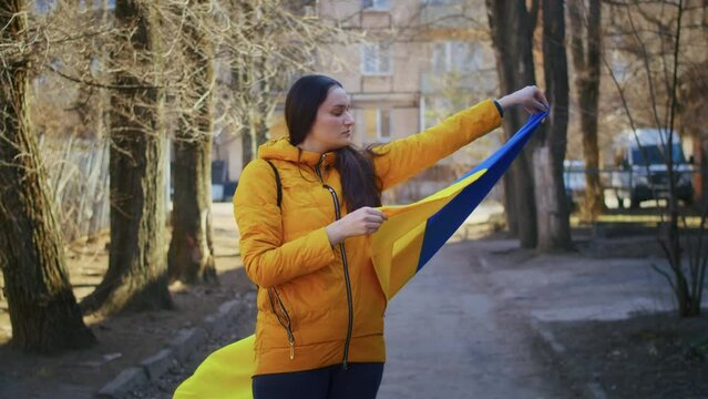 Portrait of a sad Ukrainian woman with a Ukrainian flag and a sign. The girl is waiting for her husband from the war. War between Russia and Ukraine.