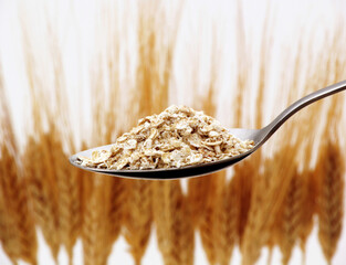 oat spoon on wheat spikes background.