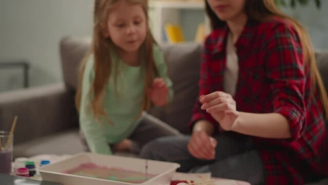 Sisters finish eggs coloring for Easter and give high five in living room slow motion. Ebru design technique and Christian holiday traditions